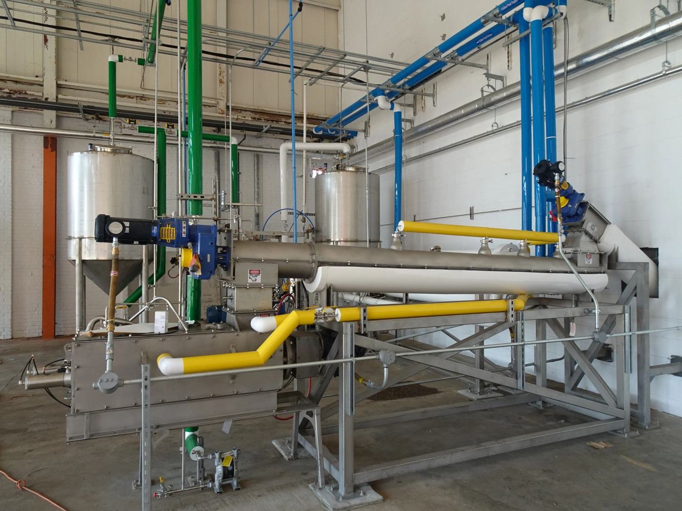 Industrial process line with screw conveyor, tanks and color-coded piping